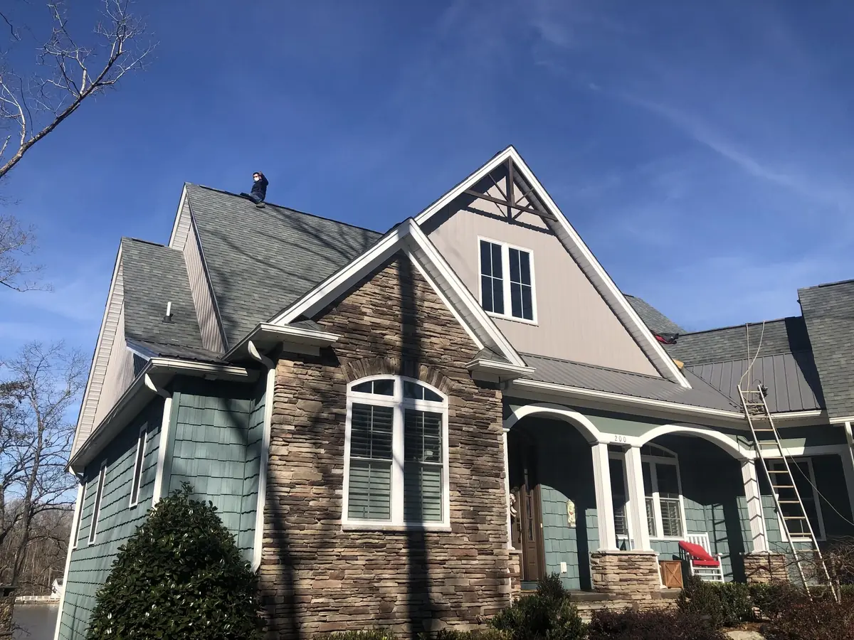 A completed home with stone-and-shingle facade, covered porch and finished landscaping