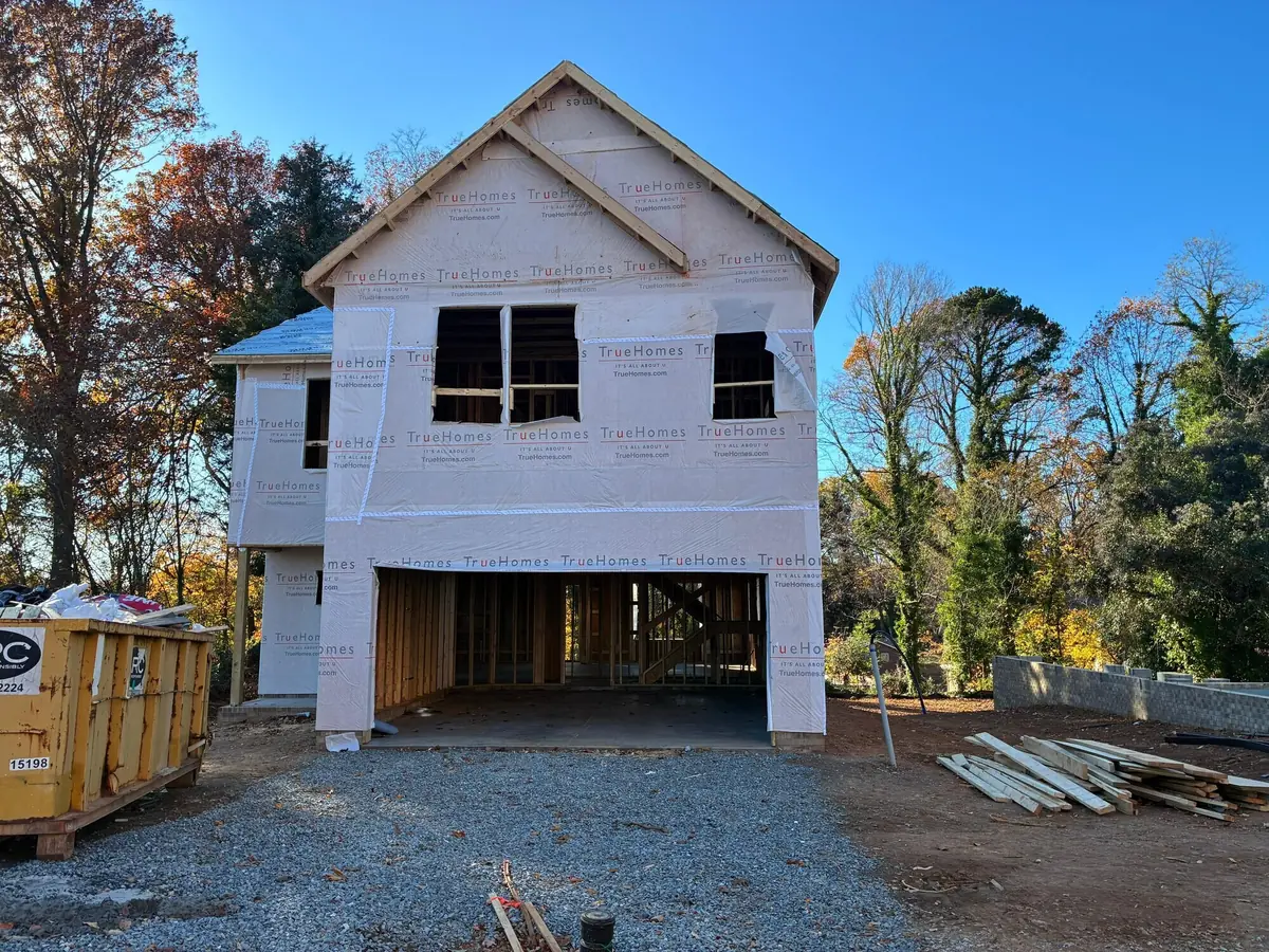 A two-storey home framed and sheathed with an open garage bay, under a clear blue sky