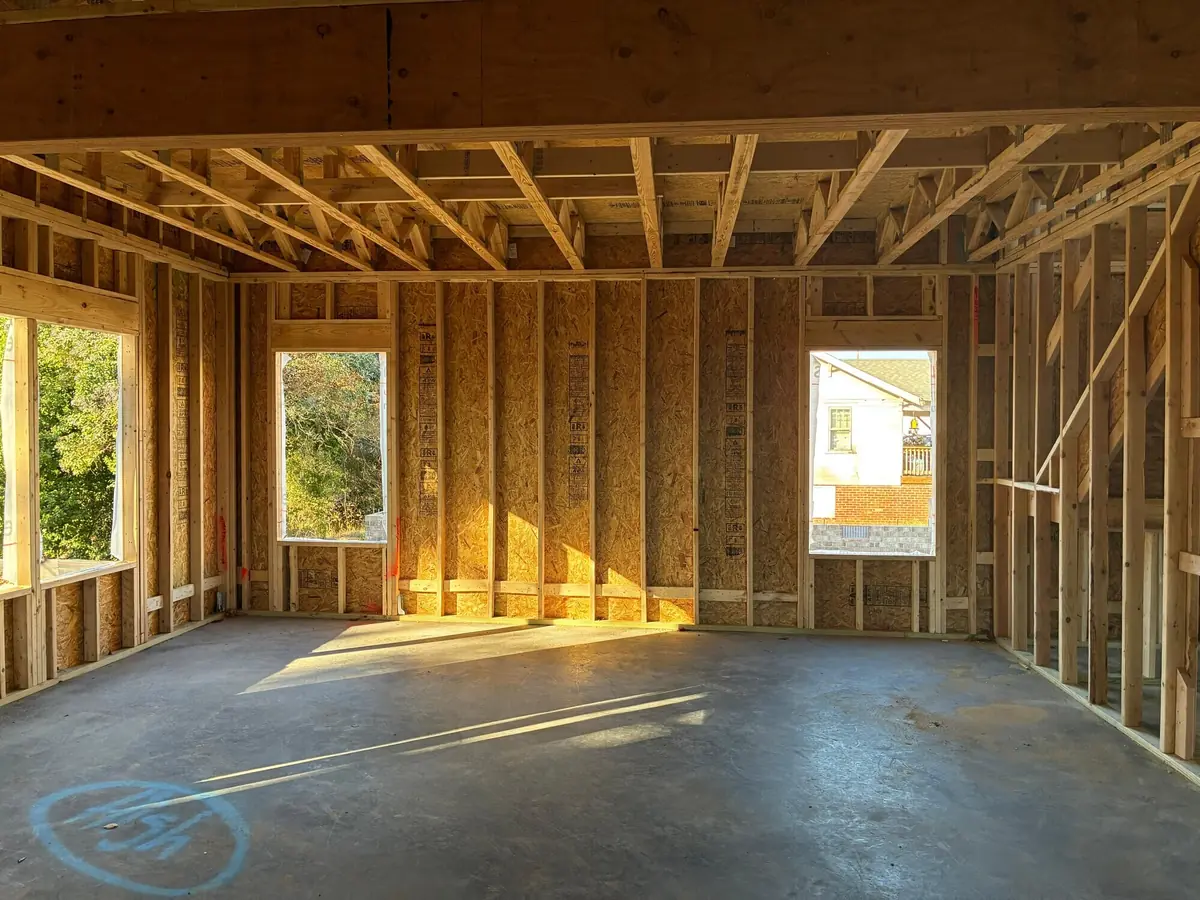 Inside a framed garage looking out through window openings, studs and headers exposed