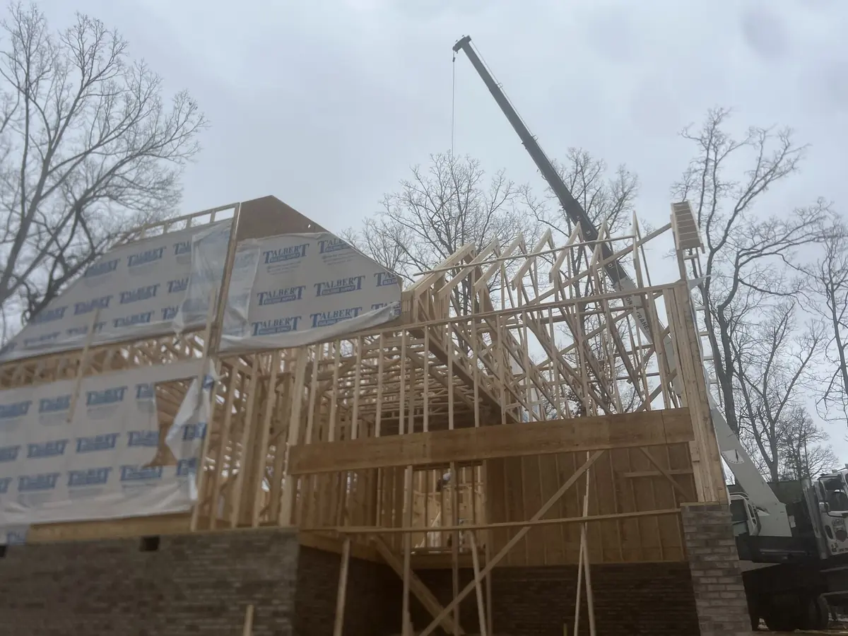 Roof trusses being set by crane on a house at framing stage